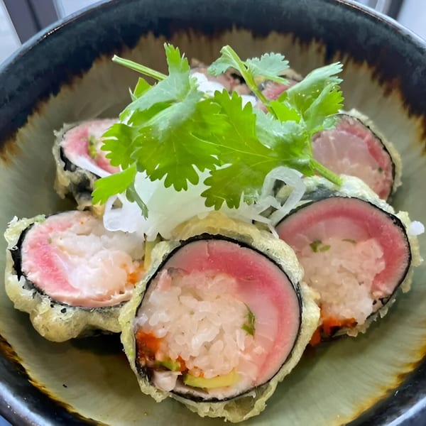 Tsukino Sushi Bar's deep-fried sushi rolls with pink fish, rice, and green garnish in a bowl.