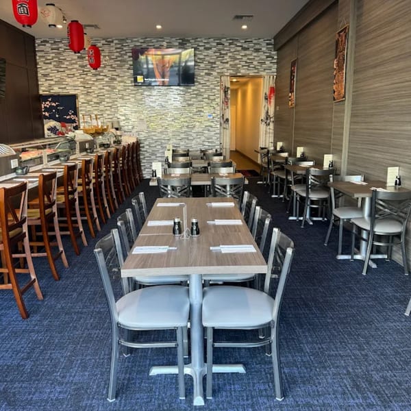 Interior of Tsukino Sushi Bar with a sushi counter, dining tables, and red lanterns.